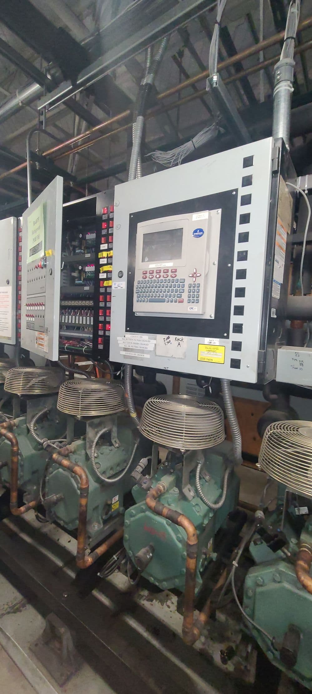 Industrial control panel with multiple compressors and electrical connections in a facility.