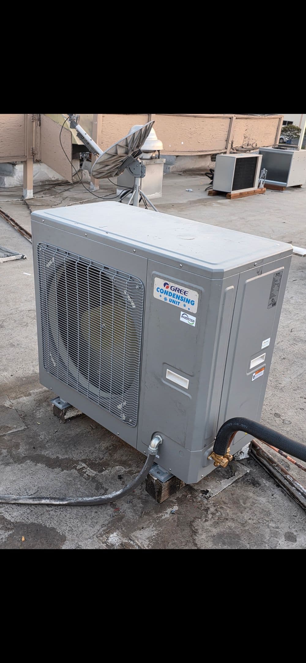Air conditioning unit on rooftop with visible piping and mounting hardware. Energy-efficient cooling.