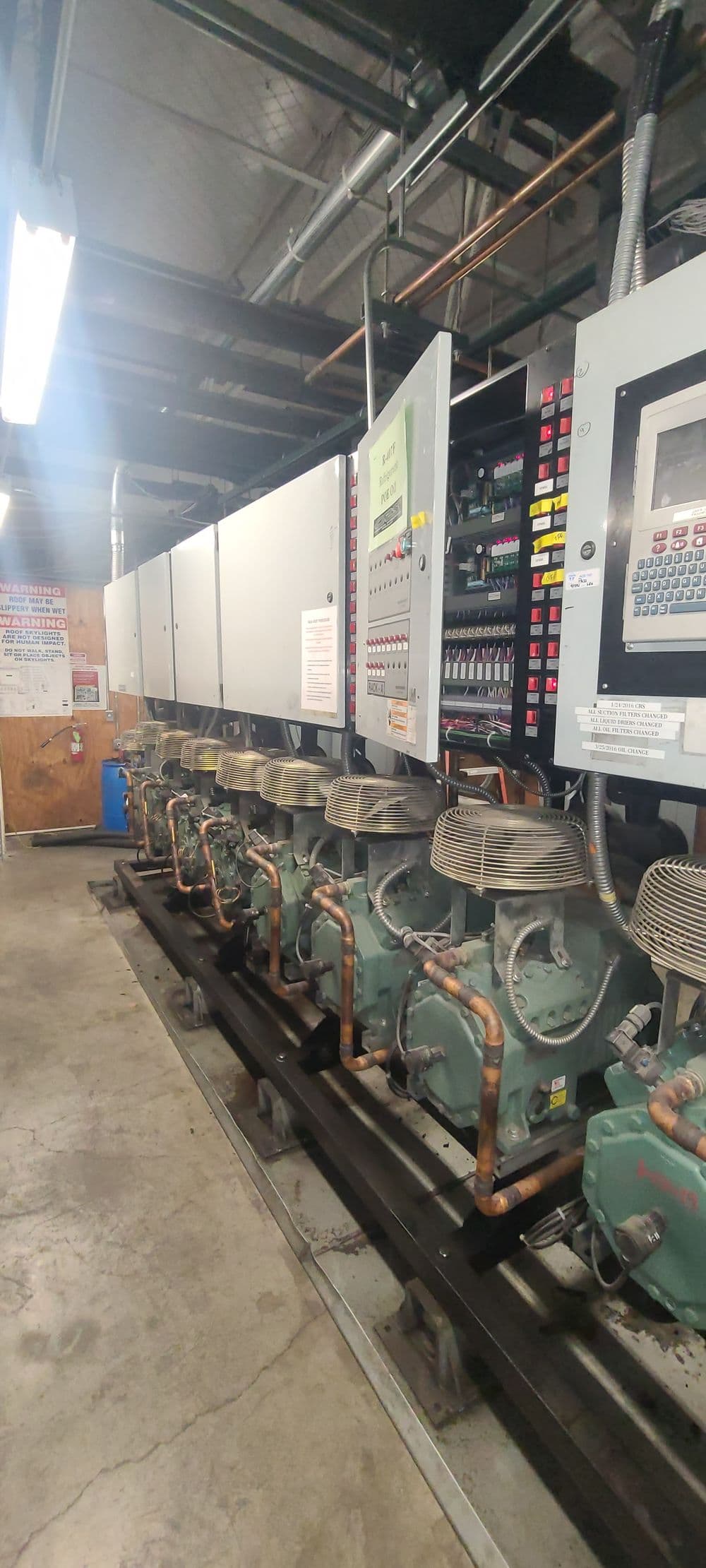 Industrial refrigeration system with multiple compressors and control panels in a facility.