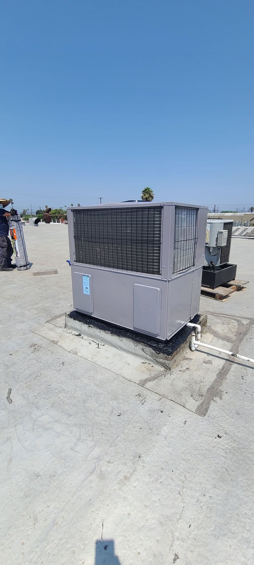 Rooftop air conditioning unit installed on a commercial building, clear blue sky background.