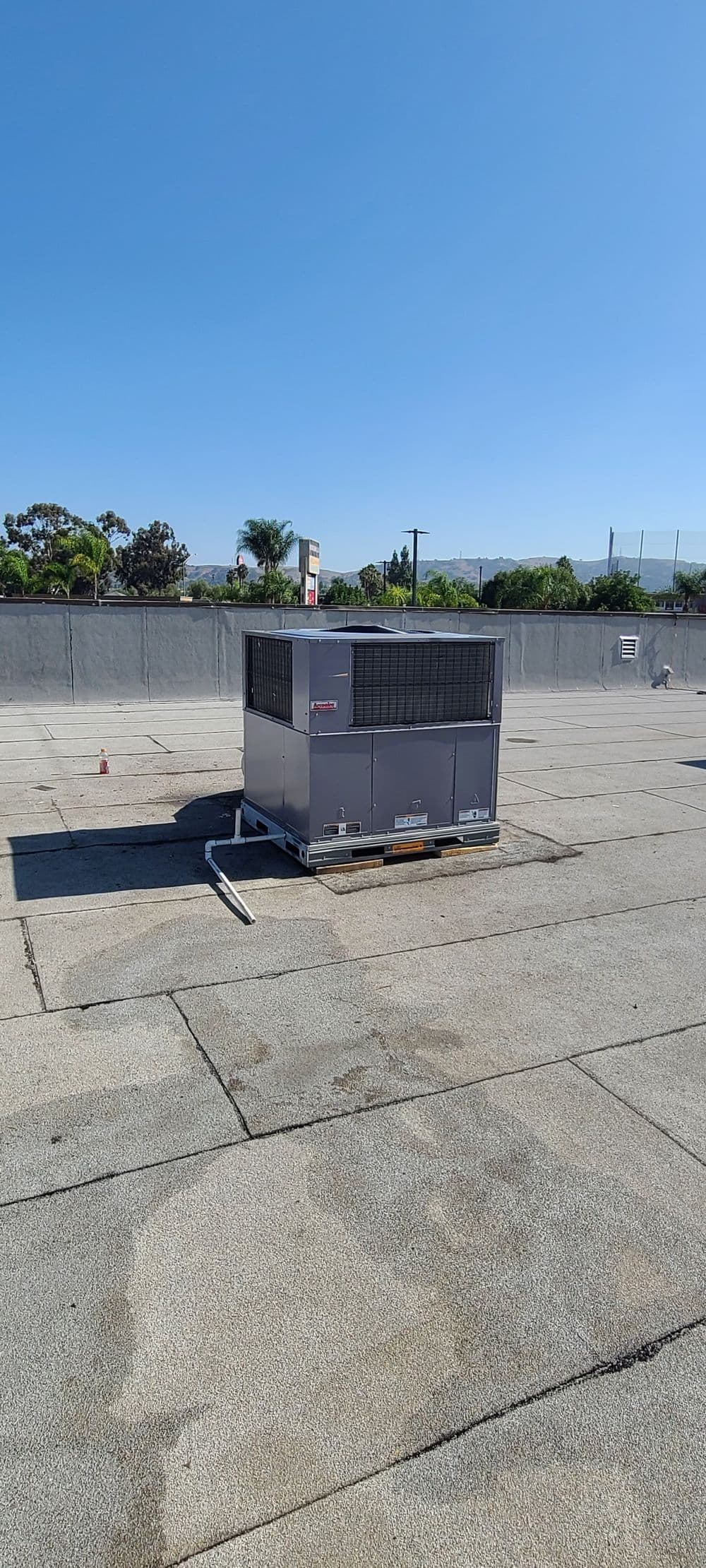 Commercial rooftop HVAC unit on a flat roof under clear blue sky.