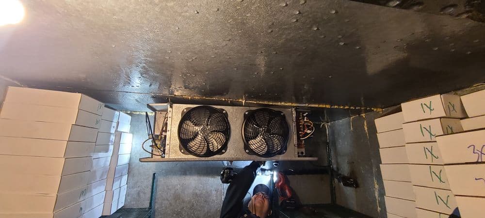 Cooling system with multiple fans inside a storage facility, surrounded by boxes.