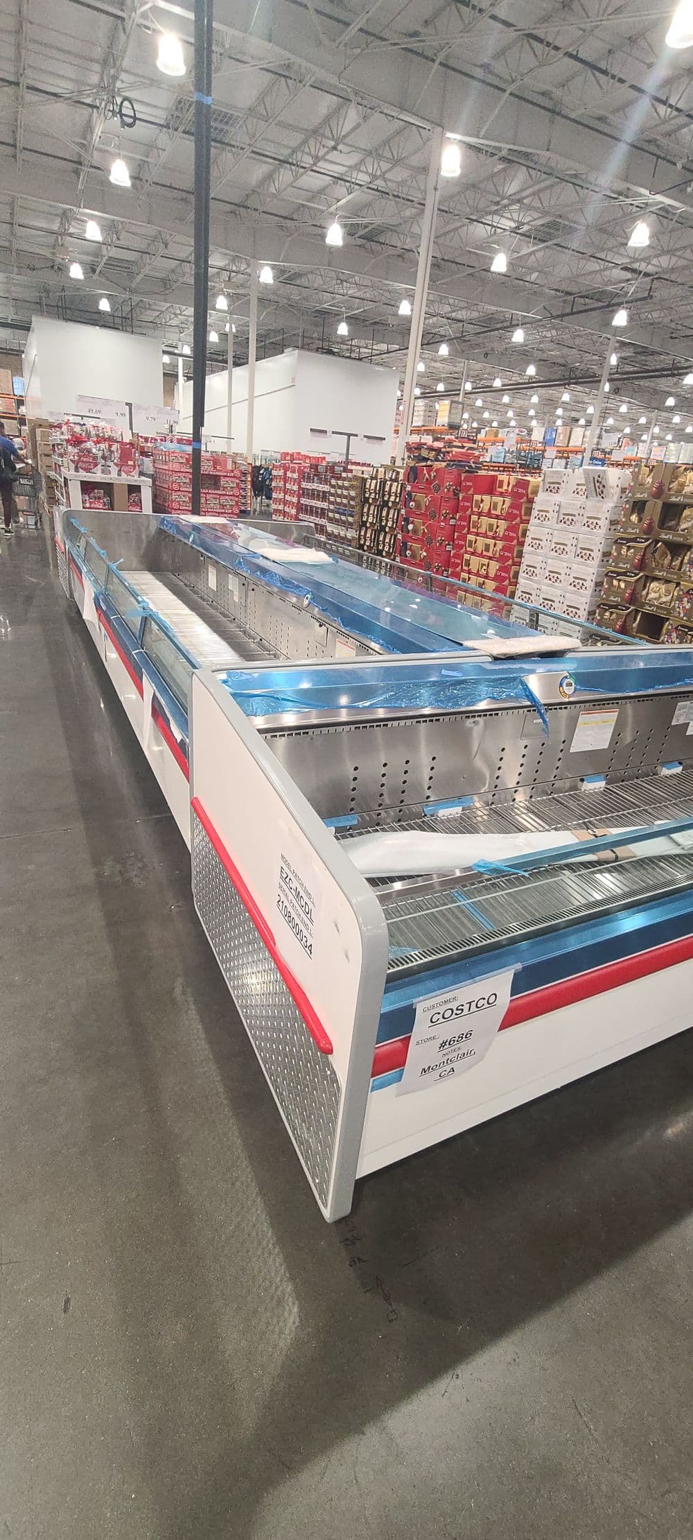 Empty freezer aisle at Costco with metal display cases and product shelves in the background.
