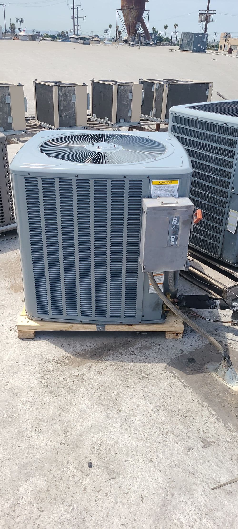 Air conditioning unit on rooftop, showcasing modern design and electrical connections.