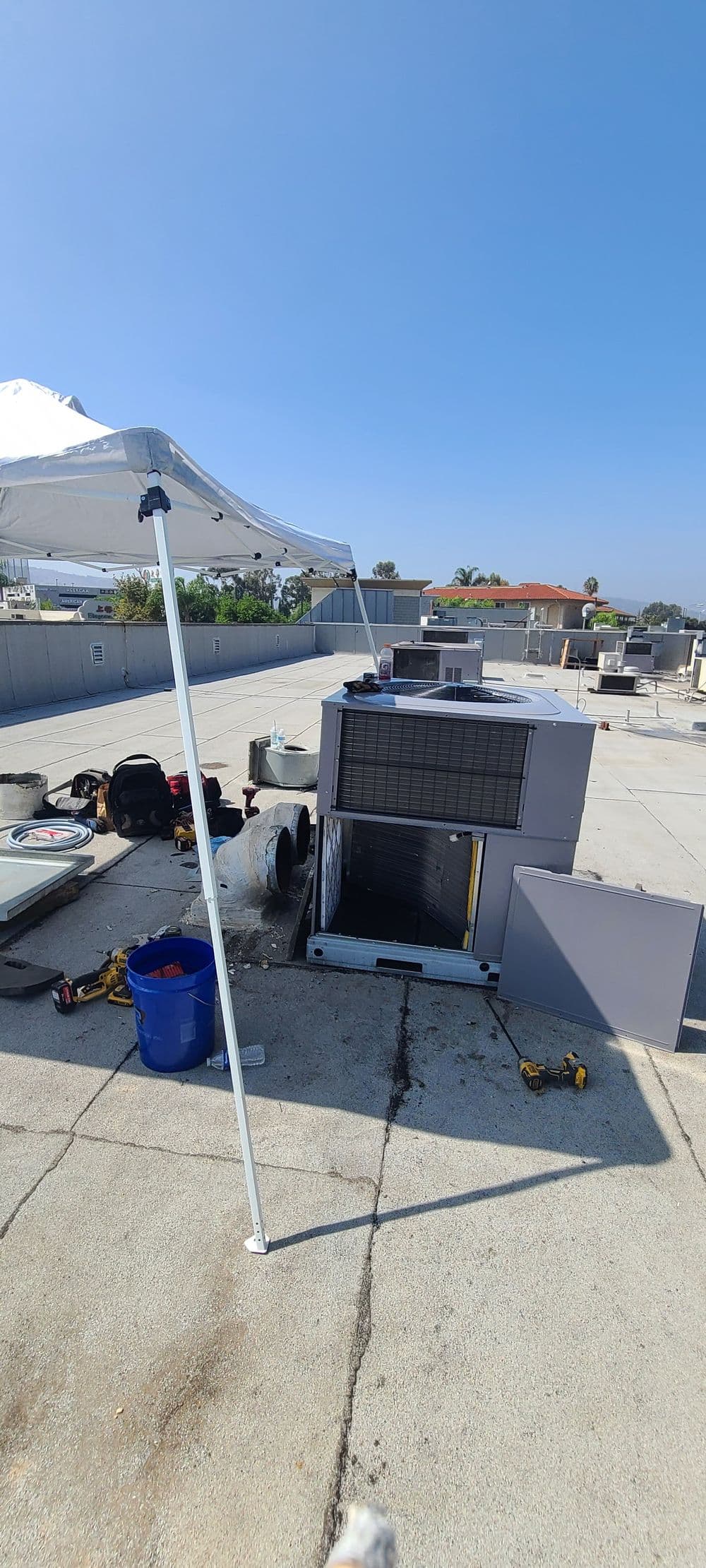 Air conditioning unit installation on a rooftop with tools and equipment visible.