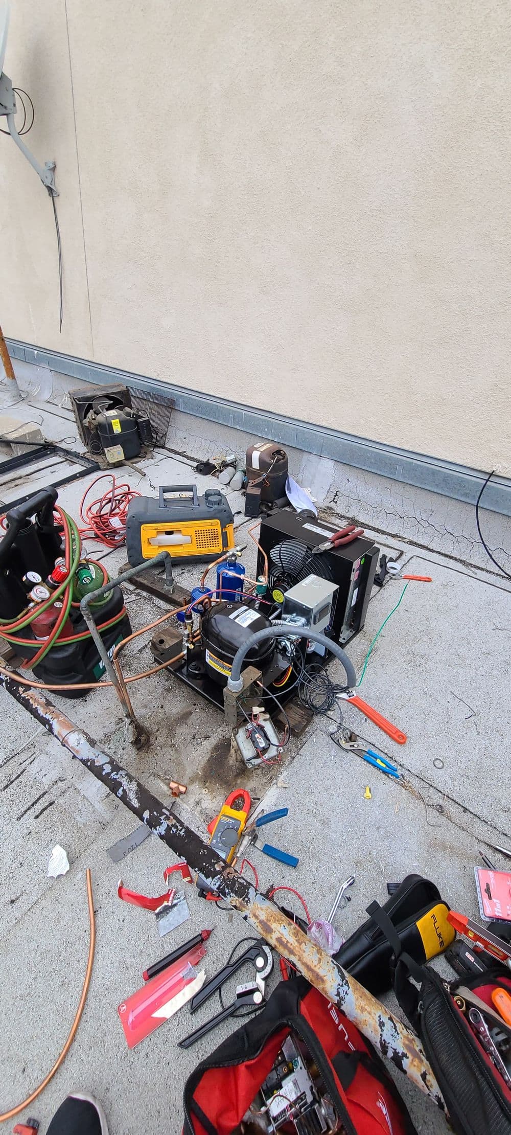 HVAC system installation on rooftop with tools and equipment scattered around.