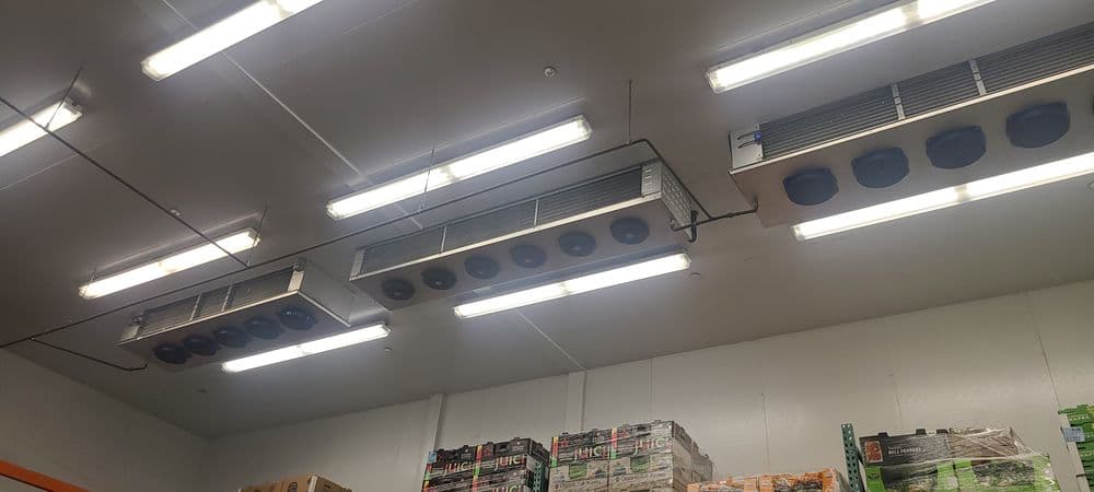 Ceiling with commercial refrigeration units and overhead lights in a storage facility.