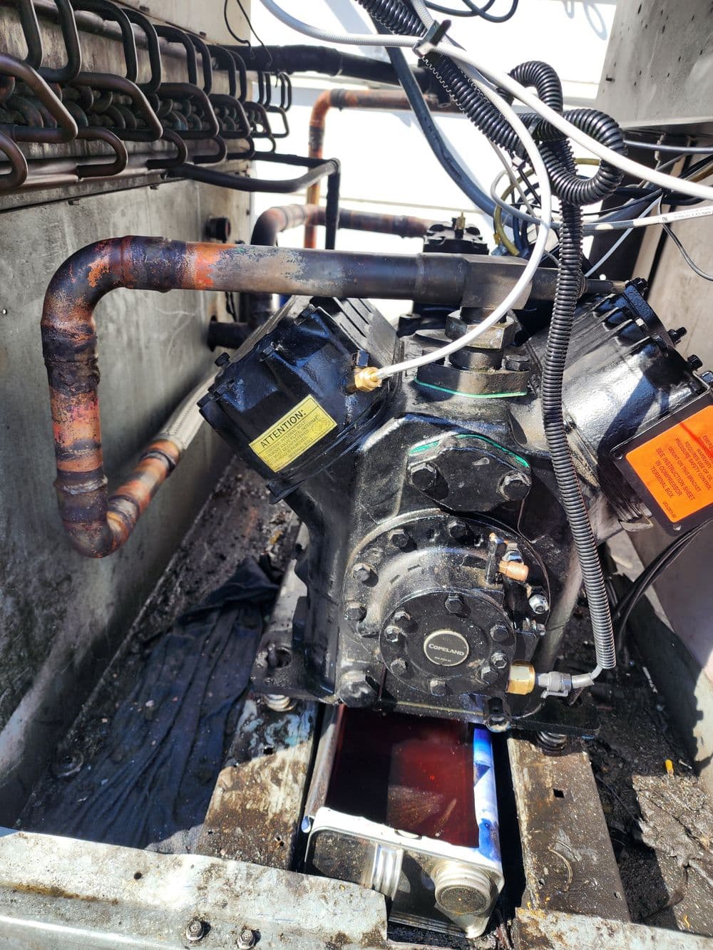 Industrial engine inside machinery with visible pipes and wiring, showcasing mechanical components.