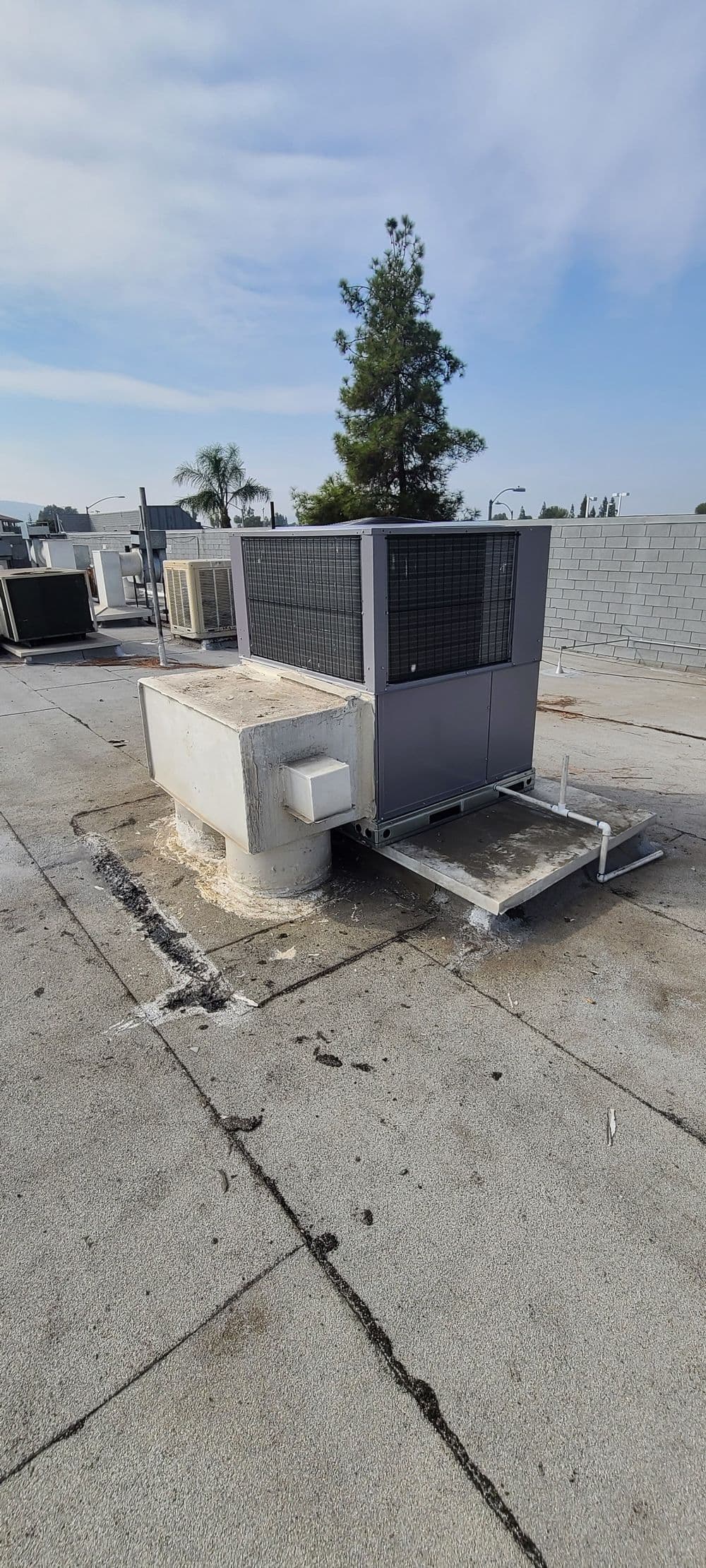 HVAC unit on a rooftop with clear blue sky and surrounding utilities visible.