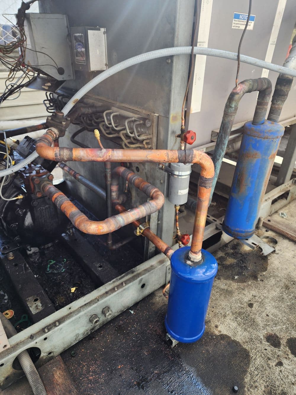 Industrial refrigeration system with copper piping and blue filter cylinders on a unit.