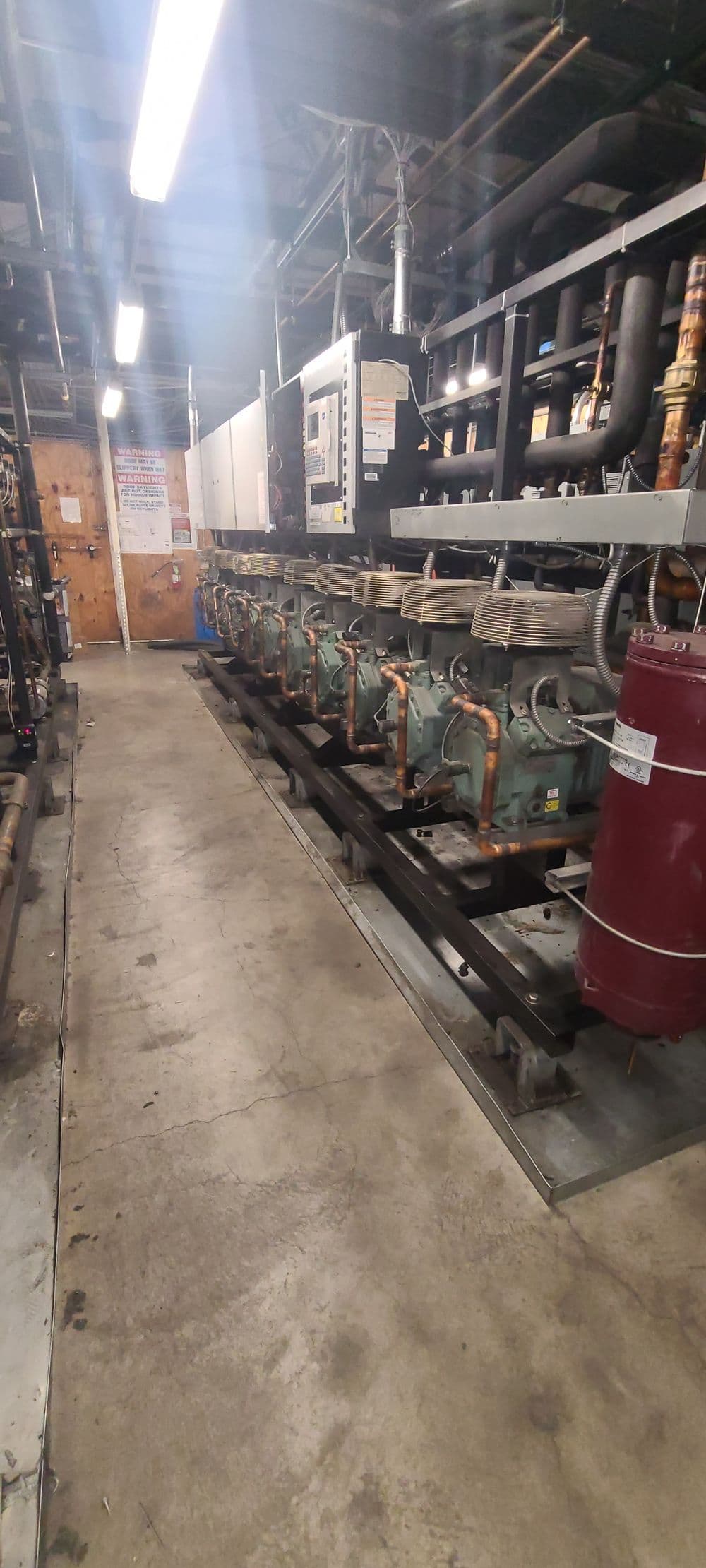 Industrial engine room featuring multiple large engines and machinery on a concrete floor.