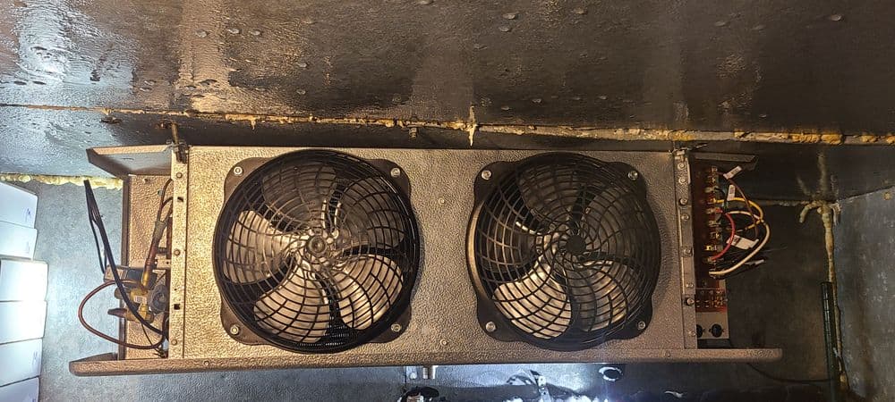 Industrial cooling system with dual fans and wiring, mounted on a wall. Efficient heat management.