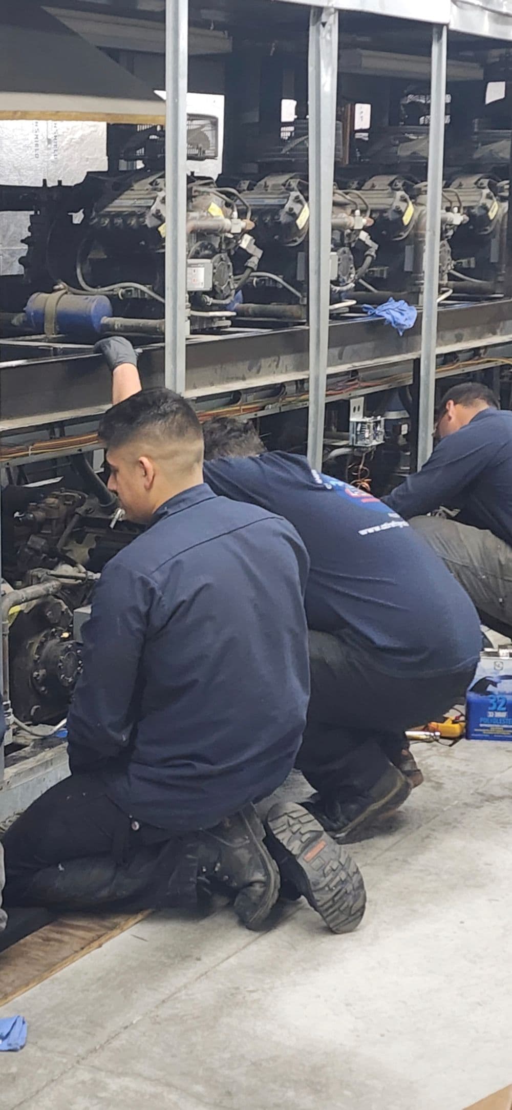 Technicians working on machinery in a workshop, focused on repairs and maintenance.