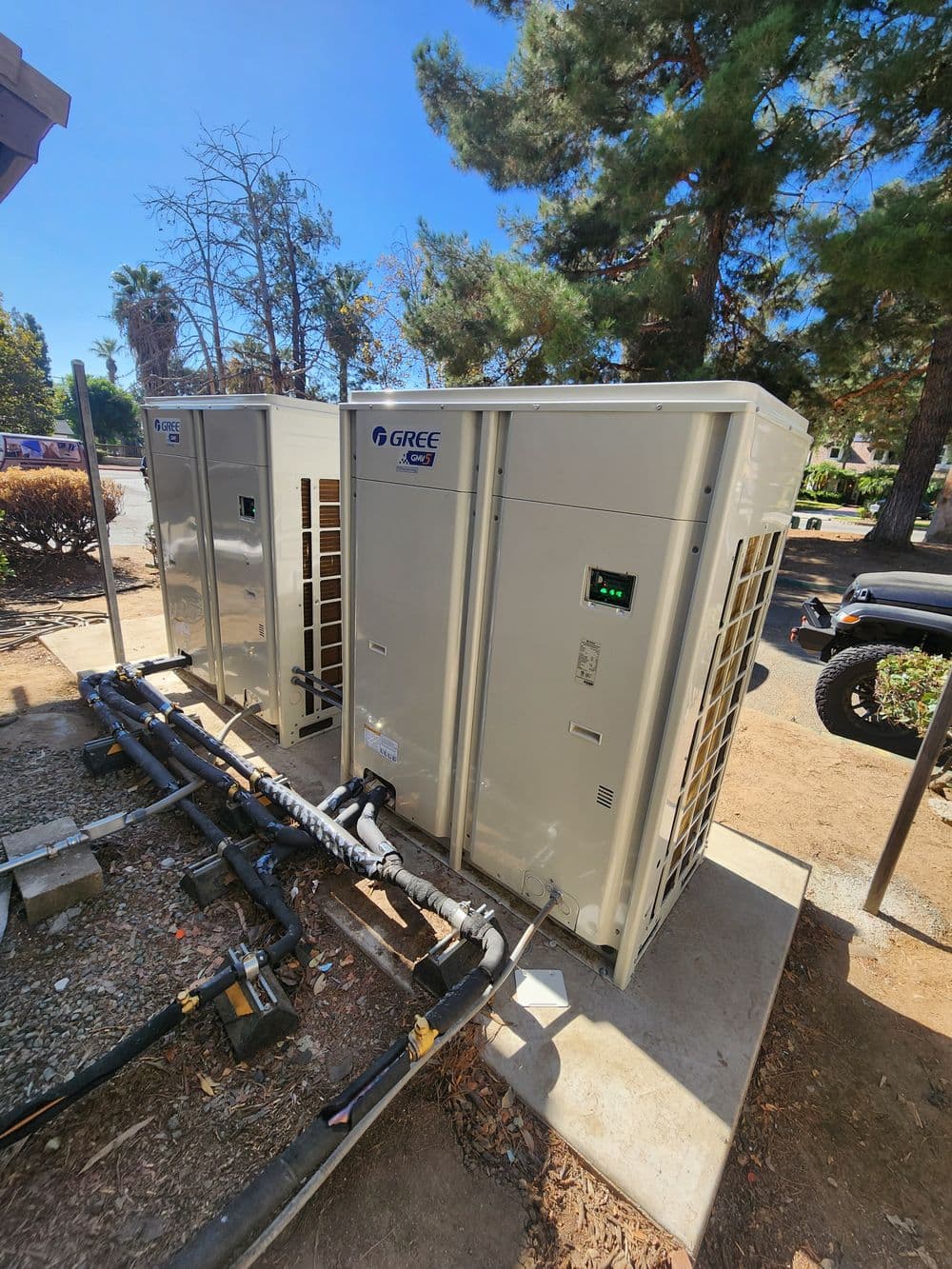 Dual GREE HVAC units outdoors, showcasing modern air conditioning system installation.