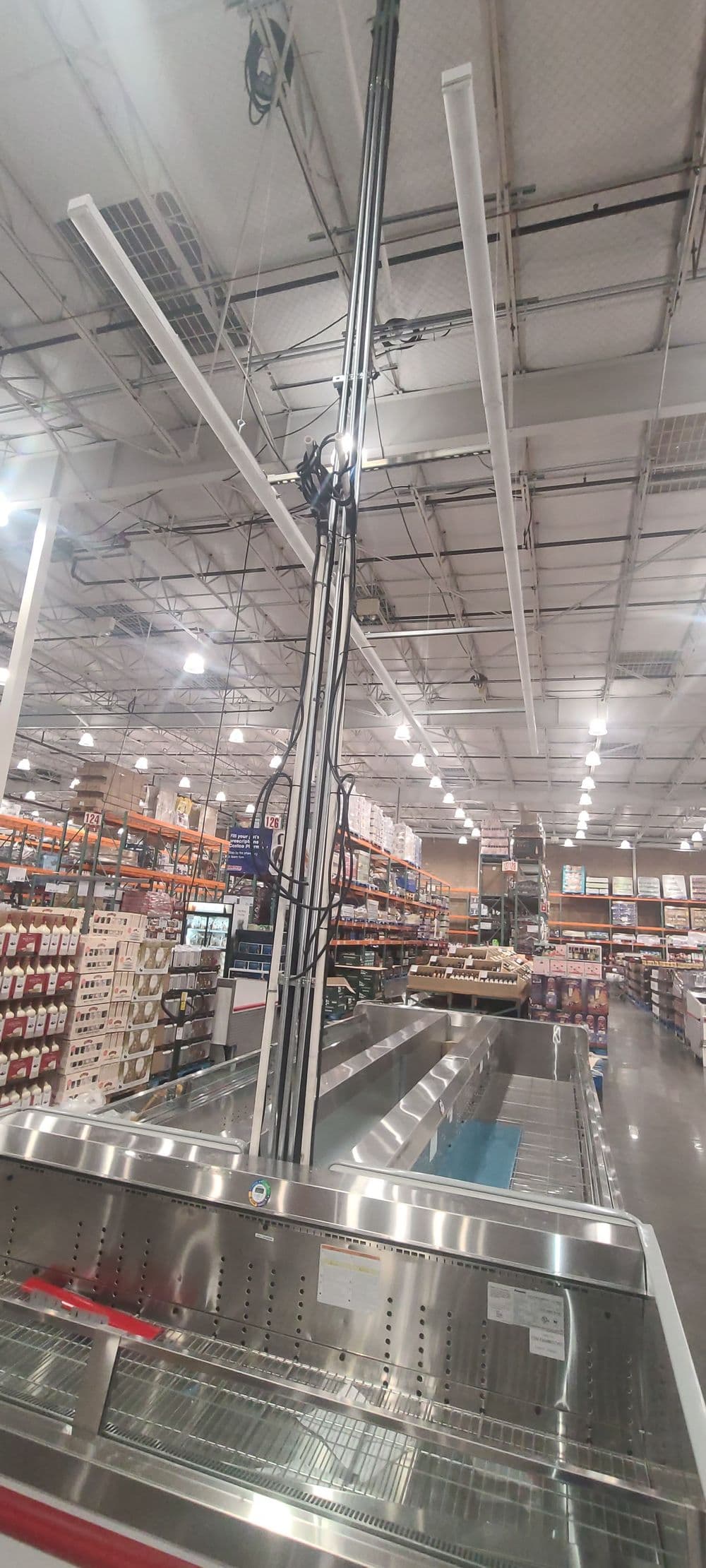 A tall ceiling-mounted fixture with overhead lights in a Costco store aisle.