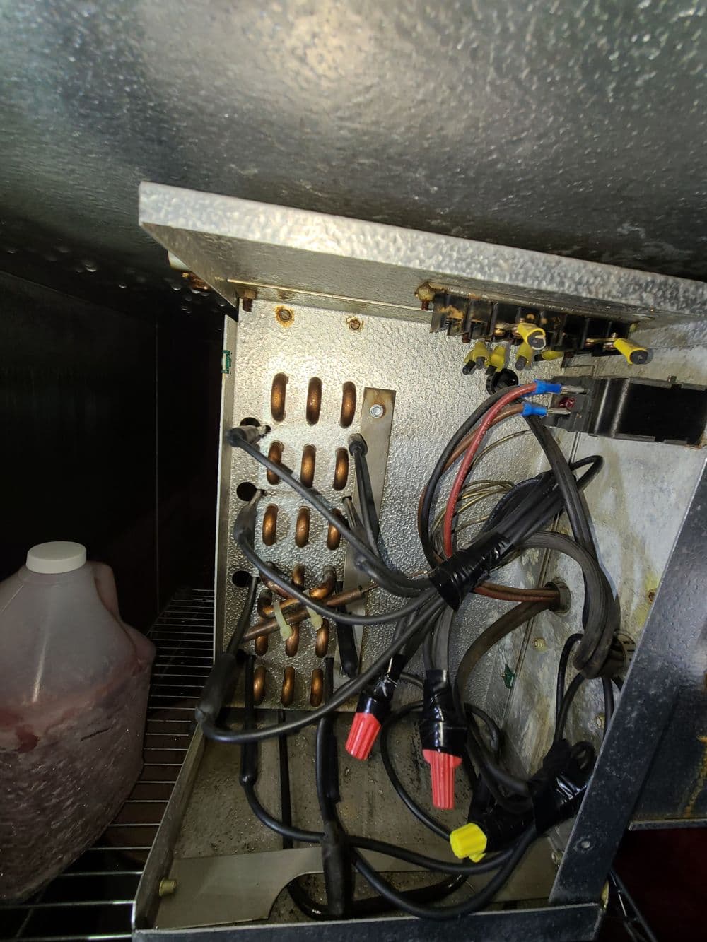 Interior view of a refrigeration unit showing copper coils and electrical connections.