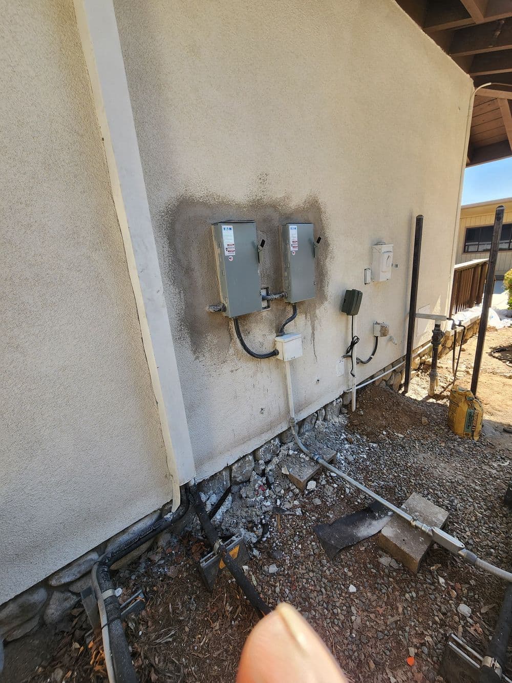 Electrical panels mounted on a wall with conduit and wiring details in a construction setting.