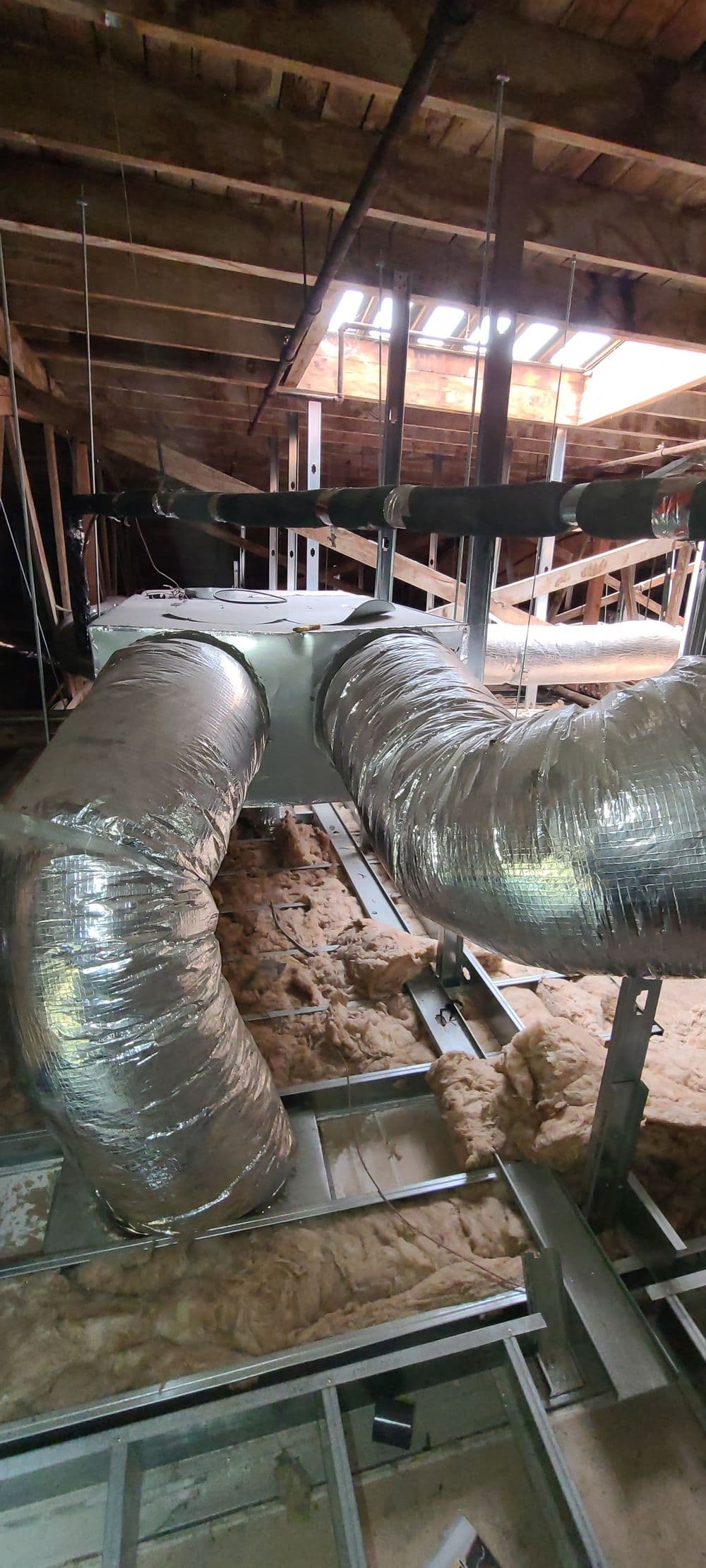 Ductwork in attic with insulation, showing installation of HVAC system components.